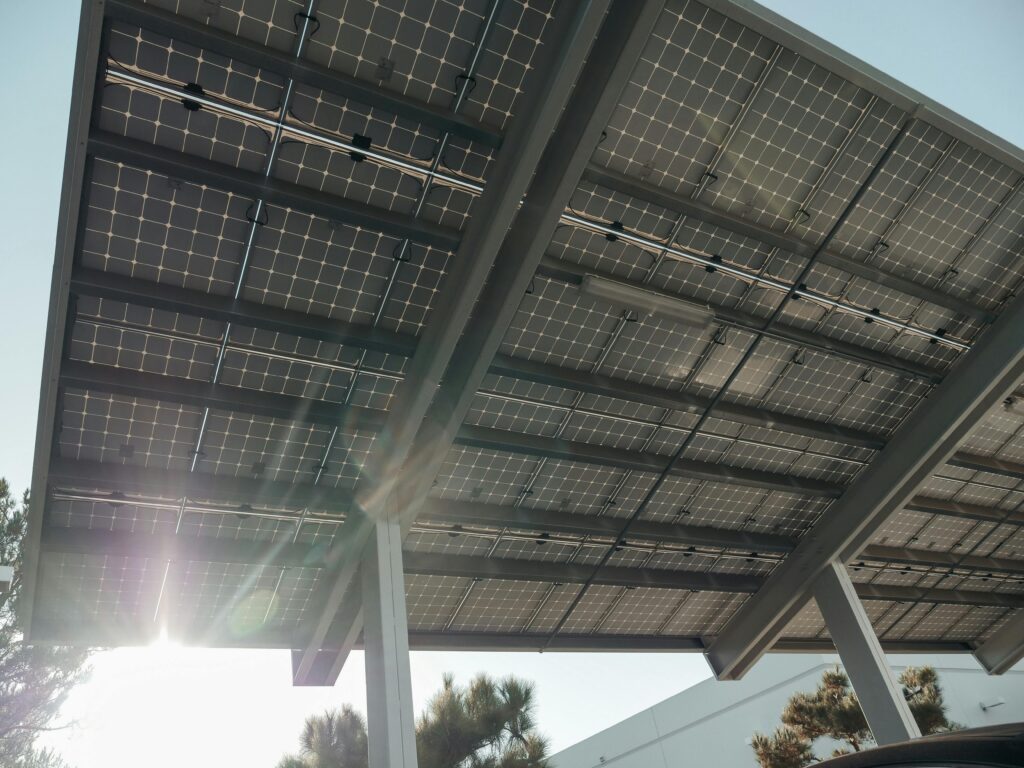 pexels-photo-9799761-9799761 Close-up of solar panels on metal structure with sunlight filtering through, emphasizing sustainable energy.